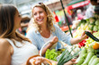 © NDABCREATIVITY - Young happy women shopping vegetables and fruits on the market