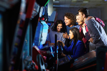 A Group Of Friends Playing Arcade Machine.