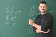 © Pixel-Shot - Handsome math teacher writing on blackboard in classroom