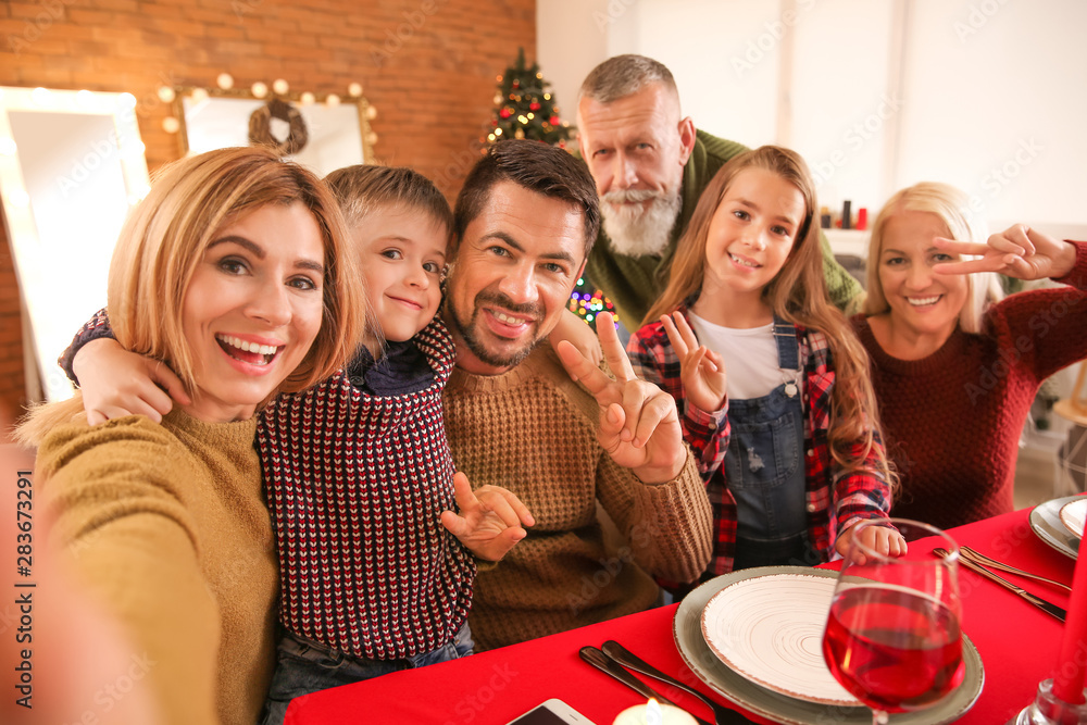 Happy family taking selfie during Christmas dinner at home