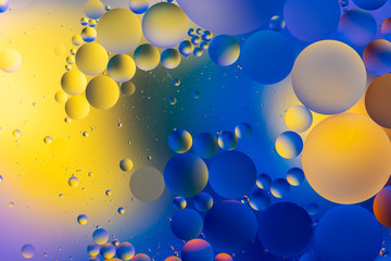 bright oily drops in water with colorful background, close-up 