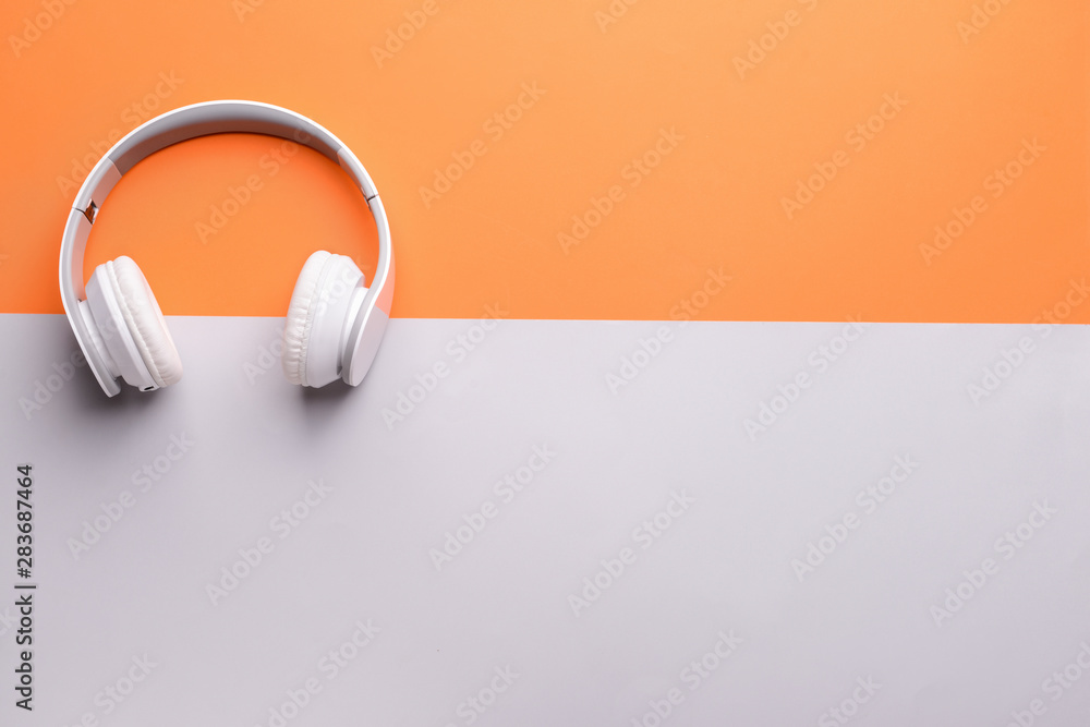 Modern headphones on color background