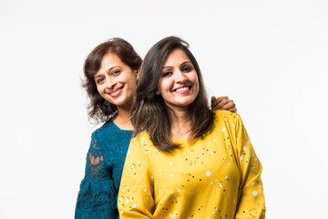 Wall Mural - Beautiful mother and adult daughter  hugging and smiling while standing isolated over white background