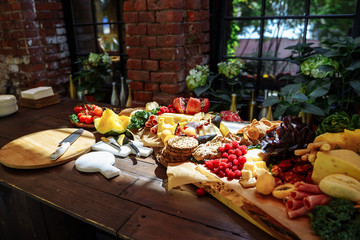 Dish of delicious snacks of cheese, prosciutto, fresh herbs, fruits and berries