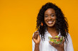 © Prostock-studio - Happy african american woman eating vegetable salad