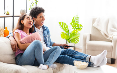 Wall Mural - Watching Comedy Movie. Loving Teenage Couple Resting On Sofa