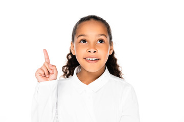 cheerful african american schoolgirl looking up and showing idea gesture isolated on white