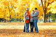 © soleg - Happy family posing, playing and having fun in autumn city park. Children and parents together having a nice day. Bright sunlight and yellow leaves on trees, fall season.