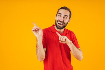 Portrait of handsome man in red t-shirt rejoicing and gesturing fingers at copyspace