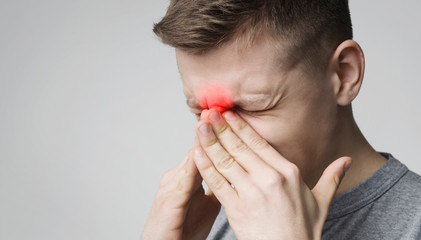 Wall Mural - Stressed young man suffering from sore nose