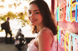 © Drobot Dean - Cheerful smiling young pretty woman at the beach party near bright led colorful wall in cafe bar.