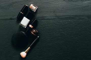 Top view of make-up products on the left side of a black background with copy space - Minimalist flatlay with beauty items for women