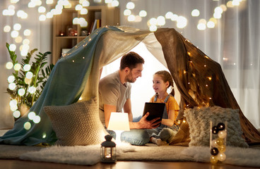 Poster - family, hygge and technology concept - happy father and little daughter with tablet pc computer in kids tent at night at home