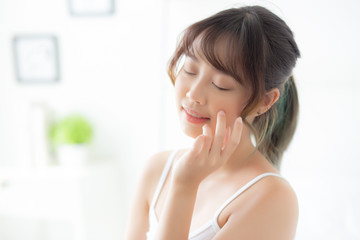 Beautiful portrait asian woman makeup of cosmetic, girl hand touch cheek and smile attractive, face beauty perfect with wellness in the bedroom with skin care and healthcare concept.