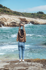 Wall Mural - woman walking by rocky sea beach at sunny windy day. summer vacation