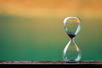 Hourglass on wooden and colorful background