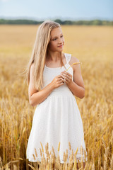 nature, harvesting and eco concept - smiling young girl holding spikelet of wheat on cereal field in summer