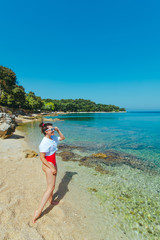 Wall Mural - sexy woman in red swimsuit and white t-shirt at sea beach