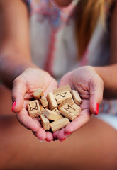 Wall Mural - Wooden runes for fortune telling lie in female hands. Stretches them forward