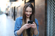 © Antonioguillem - Happy girl walks and checks smart phone in the street