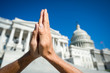 Hands held together in prayer in front on Capitol Building in Washington DC, USA