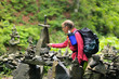 © Андрей Репетий - Woman hiker with a backpack putting stones, small rocks in the forest. The tower of falls.