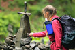 © Андрей Репетий - Traveling girl with a backpack putting stones and small rocks in the forest. The tower of falls.