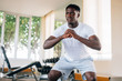 © twinsterphoto - Concentrated fit African American man in sportswear warming up and doing squat exercise during workout. Young sportsman squatting in gym