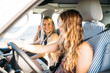© ManuPadilla - A pretty blonde girl smiling looks at her friend chestnut hair driving