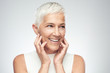 © chika_milan - Beautiful smiling senior woman with short gray hair posing in front of gray background. Beauty photography.