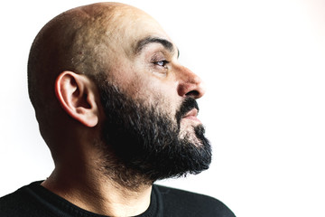 Close-up portrait, profile, of a bearded bald man with white background