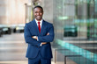 © elnariz - Modern African American CEO portrait standing confidently, with arms crossed, at swanky luxurious office building