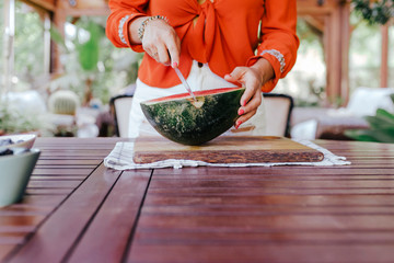 Wall Mural - young woman preparing a healthy recipe of diverse fruits, watermelon, orange and blackberries. Using a mixer. Homemade, indoors, healthy lifestyle