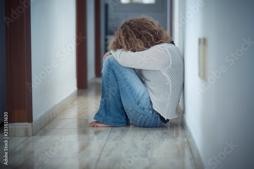 Loneliness and depression disease concept with sad woman hug herself sit down on the floor a home alone - protection needed and violence against woman and wife image