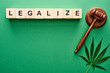 top view of green cannabis leaves and legalize lettering on wooden blocks near gavel on green background