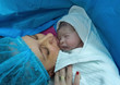 Newborn baby with mother in hospital, seconds after birth.