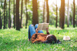 canvas print picture - A beautiful Asian woman lying and reading a book in the park