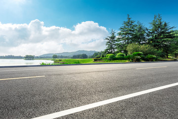 Country asphalt road and green woods with mountain nature landscape in summer