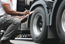 Auto Mechanic Is Checking The Truck's Safety Maintenance Checklist. Lorry Fixing. Truck Inspection Safety Of Semi Truck Wheels Tires.	
