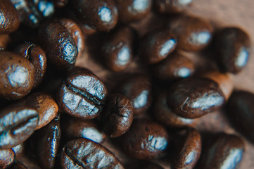 Freshly roasted scattered dark coffee beans, with mood filter, close up