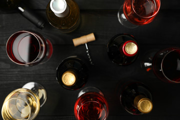 Bottles and glasses with different wine on wooden background, top view