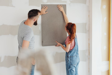 Young couple testing out a roll of wallpaper