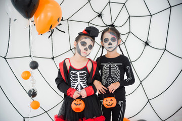 Wall Mural - Two  asian girls in skeleton costume with makeup standing in room with Halloween decoration.