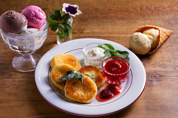 Wall Mural - Cottage cheese pancakes. Syrniki with fresh mint, sour cream and strawberry jam, ice cream - dessert concept