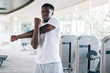 © twinsterphoto - Athletic African American man standing and stretching during workout in gym on daytime. Sportsman warming up before training