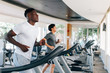 © twinsterphoto - Side view of multiracial sportsmen working out on treadmills in gym on daytime. Multiethnic males running on treadmills