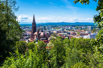 Germany, Stunning view over skyline, cityscape and roofs of city freiburg im breisgau surrounding famous muenster cathedral from above green tree tops