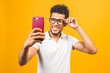 © denis_vermenko - Image of happy young african american man posing isolated over yellow background take a selfie by phone.