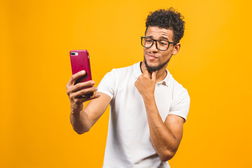 Wall Mural - Image of happy young african american man posing isolated over yellow background take a selfie by phone.