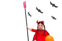 Asian Cute Little Girl Is Wearing Red Devil Costume And Holding Trident While Sitting Leaning Against The Wall. At The White Backdrop Have A Black Bats Made Of Cardboard. Halloween Festival Concept.